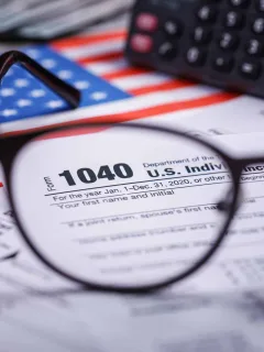 Trump tariffs 2025: Income tax with instruction, money, calculator and glasses. Tax payment and filing concept