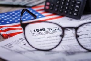 Trump tariffs 2025: Income tax with instruction, money, calculator and glasses. Tax payment and filing concept