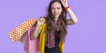 smiling-young-woman-with-shopping-bags-against-purple-backdrop